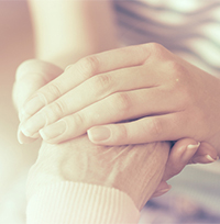 junge Hände halten alte Hand – Schutz und Betreuung