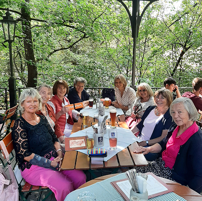 8 Damen am Biertisch vor dem Grün des Gartens