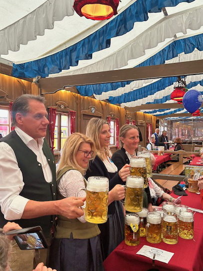der Festwirt und 3 Frauen im Dirndl mit frisch eingeschenktem Bier im Maßkrug