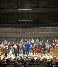 Blick auf die Bühne der Isarphilharmonie mit Musikern und Dirigenten