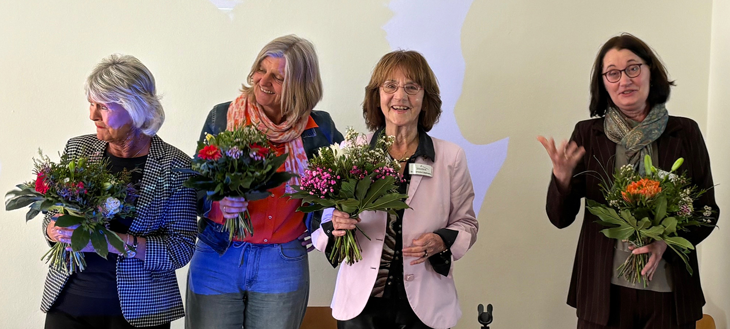 Gruppenbild mit lachenden Frauen: den Vorständinnen und Dr. Angela Lang mit Blumensträußen