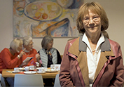 Fr. Dr. Christa Lippmann im Gemeinschaftsraum der Wohngruppe 5 mit 3 Wohnfrauen im Hintergrund