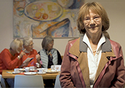 Fr. Dr. Christa Lippmann im Gemeinschaftsraum der Wohngruppe 5 mit 3 Wohnfrauen im Hintergrund