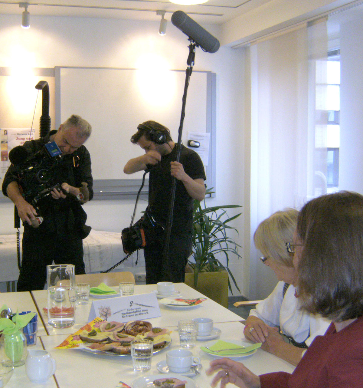 Frauen am Kaffeetisch, die Filmleute besprechen sich