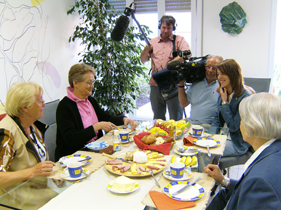 Drehteam mit 4 Frauen am üppig gedeckten Frühstückstisch
