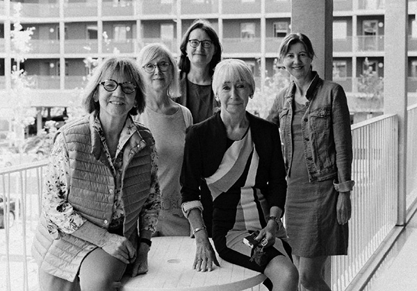 chwarzweissfoto: Christa Lippmann mit Wohnfrauen von Wohngruppe 6 im Laubengang lachen in die Kamera