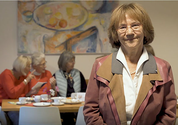 Dr. Christa Lippmann im Gemeinschaftsraum der Wohngruppe 5 mit 3 Wohnfrauen im Hintergrund